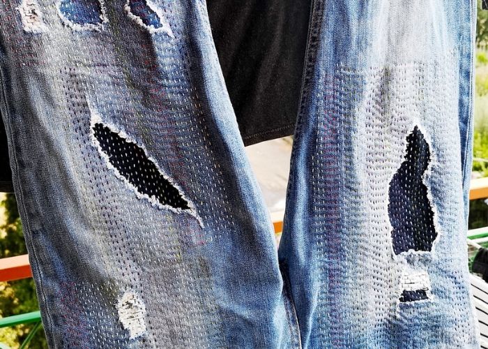 Mending holes in jeans by hand with running stitch