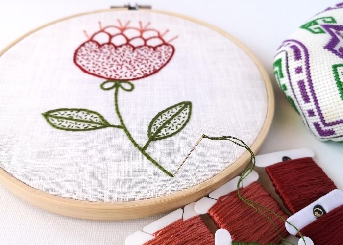 Broderie à la main en cours de réalisation. Motif floral rouge