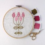 Pink modern flower embroidery in a hoop with colored floss and scissors