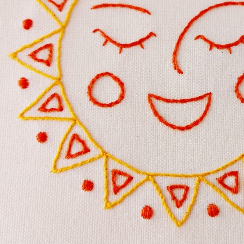 Happy sun design hand embroidered on off white cotton canvas