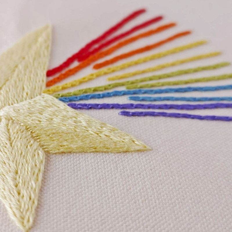 Yellow star with rainbow tail embroidered on light colored cotton fabric