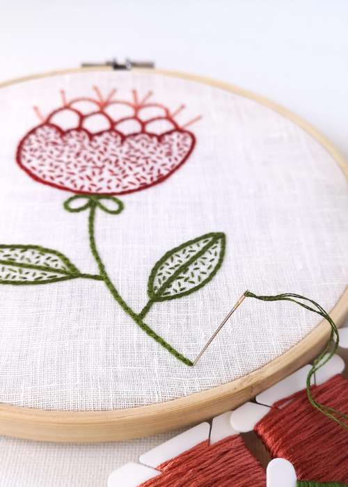 red flower embroidery in a hoop on white linen
