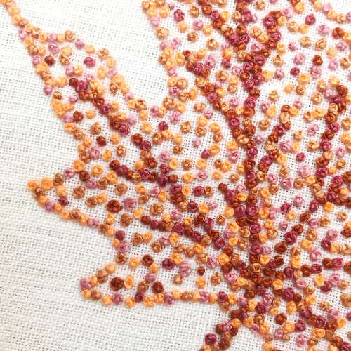 Autumn leave embroidered with French knots in brown and light orange colors