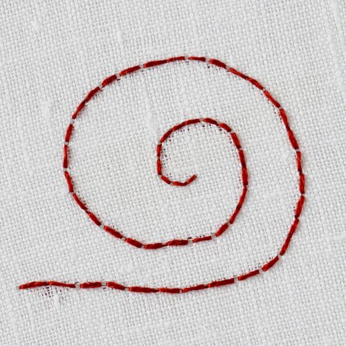 Back stitch embroidery in circle in dark red thread on white fabric