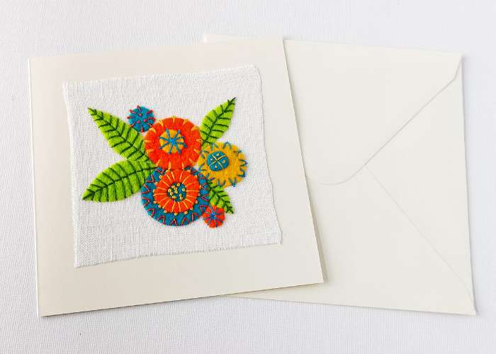 White postcard with a colorful applique hand embroidered on white linen fabric