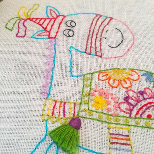 Details of hand embroidered horse - colorful threads on white linen