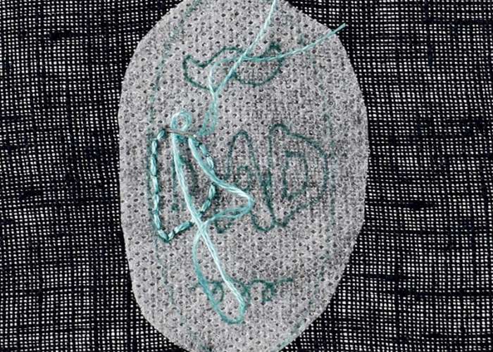 Broderie sur le tissu foncé avec un stabilisateur soluble à l'eau pour le transfert du motif