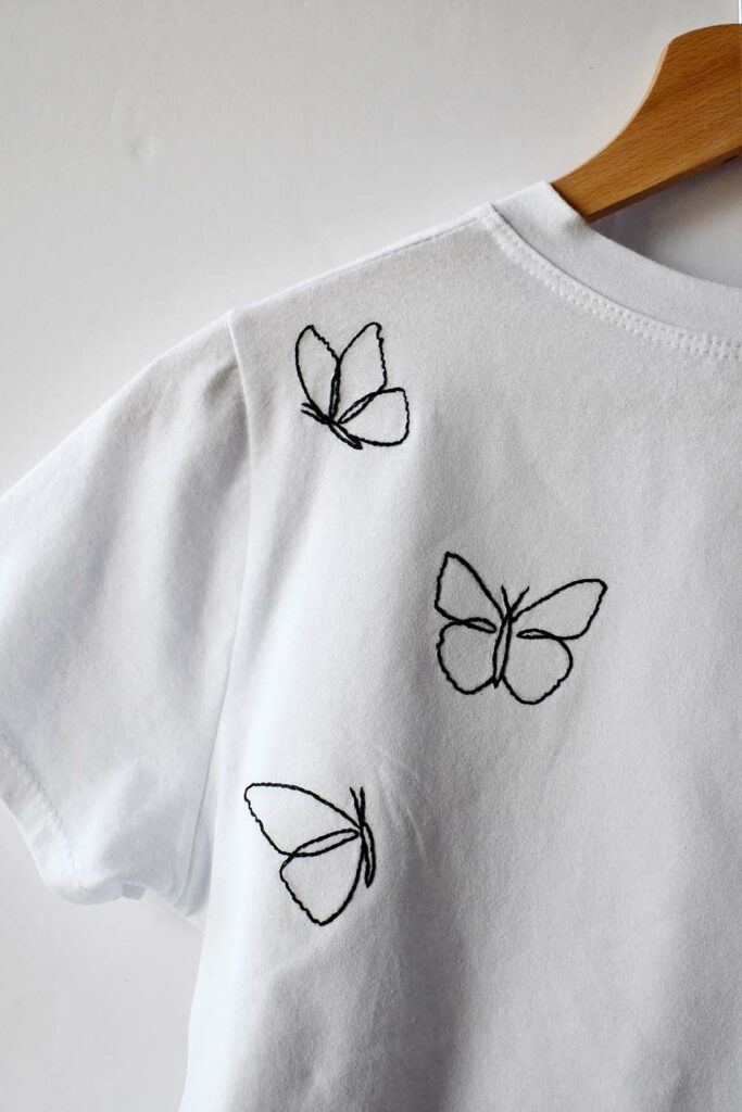 White t-shirts with hand embroidered butterflies. Black embroidery floss, outlines only