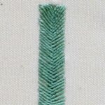 Fishbone stitch bar with green threads on white canvas