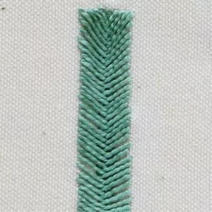 Fishbone stitch bar with green threads on white canvas