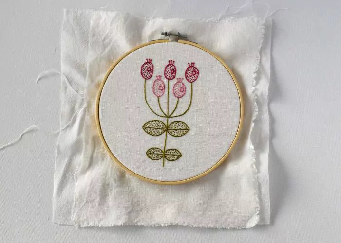 Pink flowers embroidery on white fabric stretched in a hoop