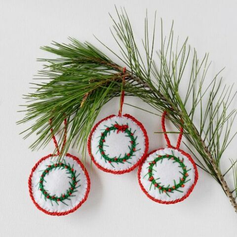 3 round ornaments with embroidery and a branch