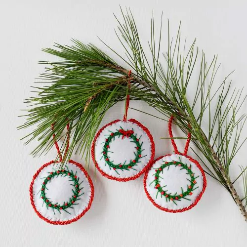 3 round ornaments with embroidery and a branch