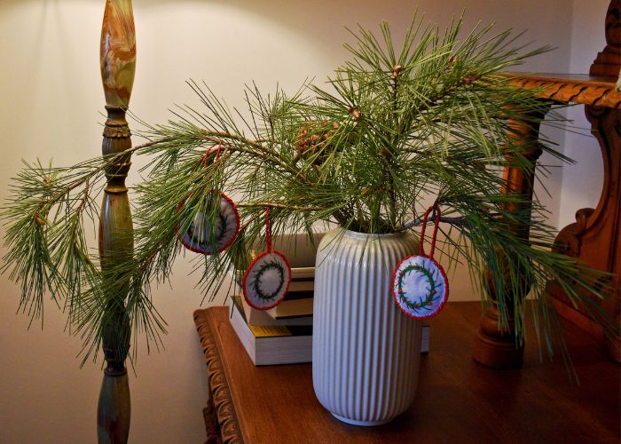 Pine tree branch in a vase decorated with handmade ornaments