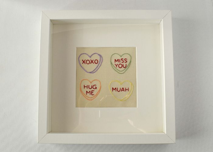 Candy hearts embroidery framed in a white shadowbox frame