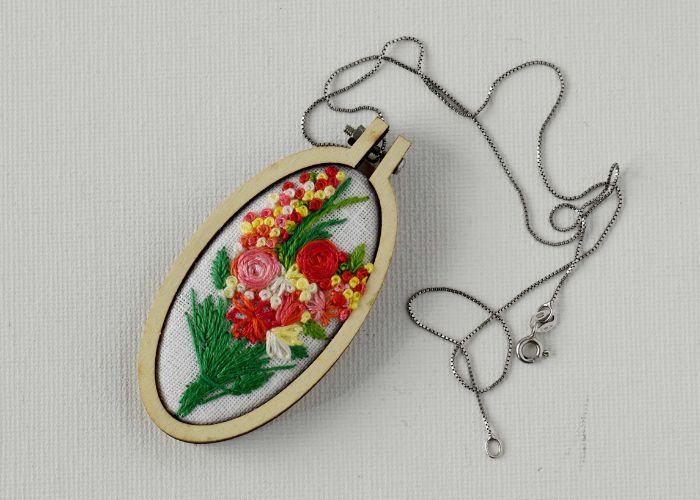 Embroidered pendant framed in a mini hoop with floral bouquet
