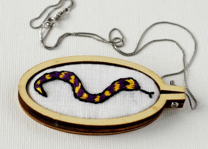 Pendant with a snake embroidery framed in a mini hoop