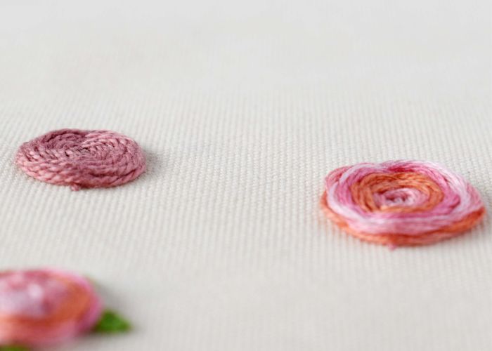 Pink flowers hand embroidered with woven wheel stitch on white fabric
