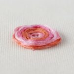 Woven spider wheel flower embroidered with pink variegated floss