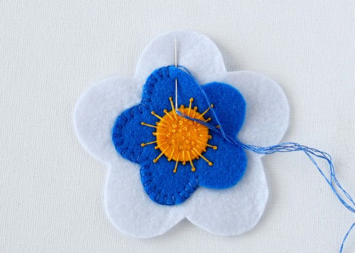 Asegure el borde de la flor azul con puntada de manta