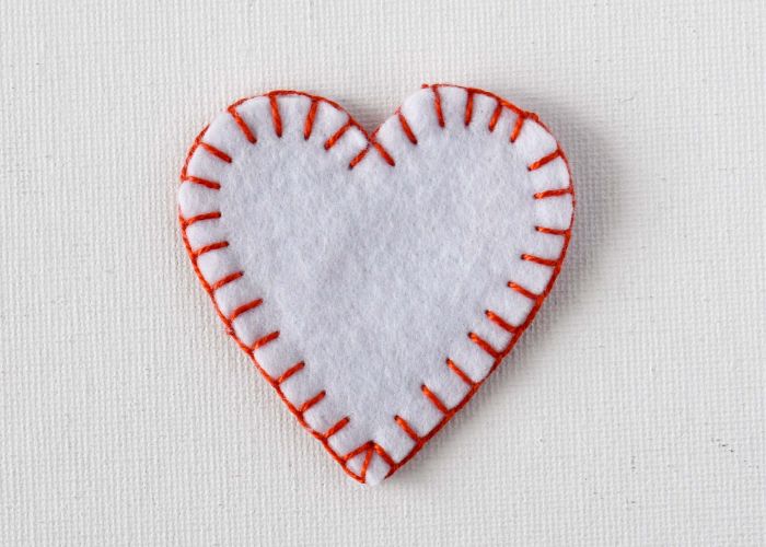 Point de couverture pour la couture ornement de cœur en feutre blanc
