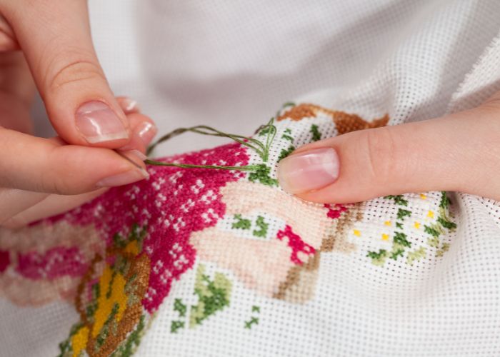 Hands making cross stitch