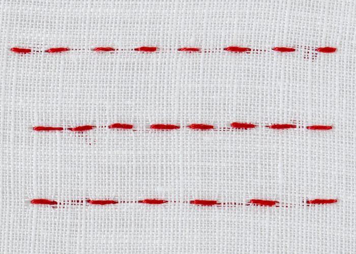 Open backstitch embroidery with red floss