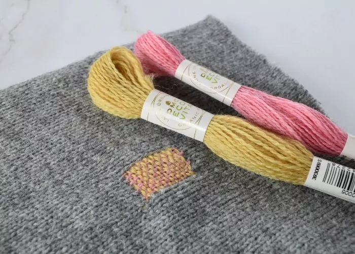 Weave stitch mending with contrasting colors of yarn image