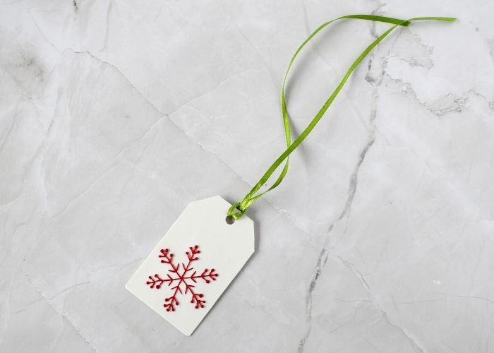 Hand embroidered Christmas gift tag with snowflake and a ribbon for hanging image