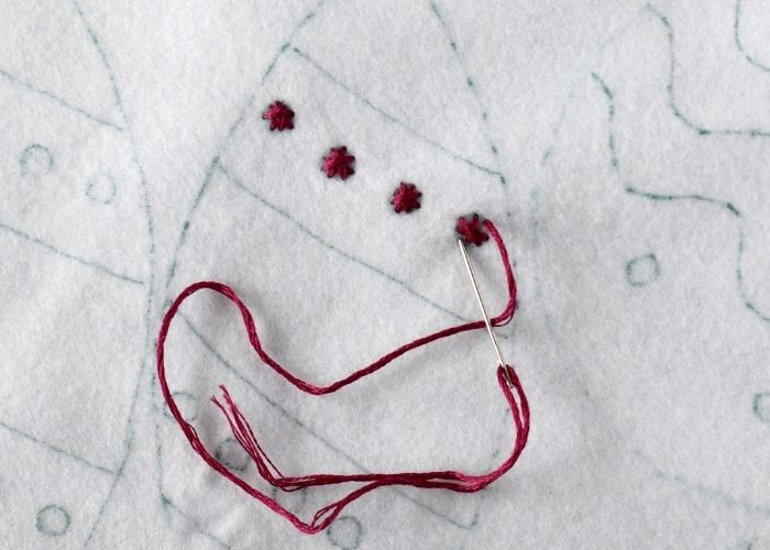 Star stitch embroidery with red floss on felt ornament step 2 image
