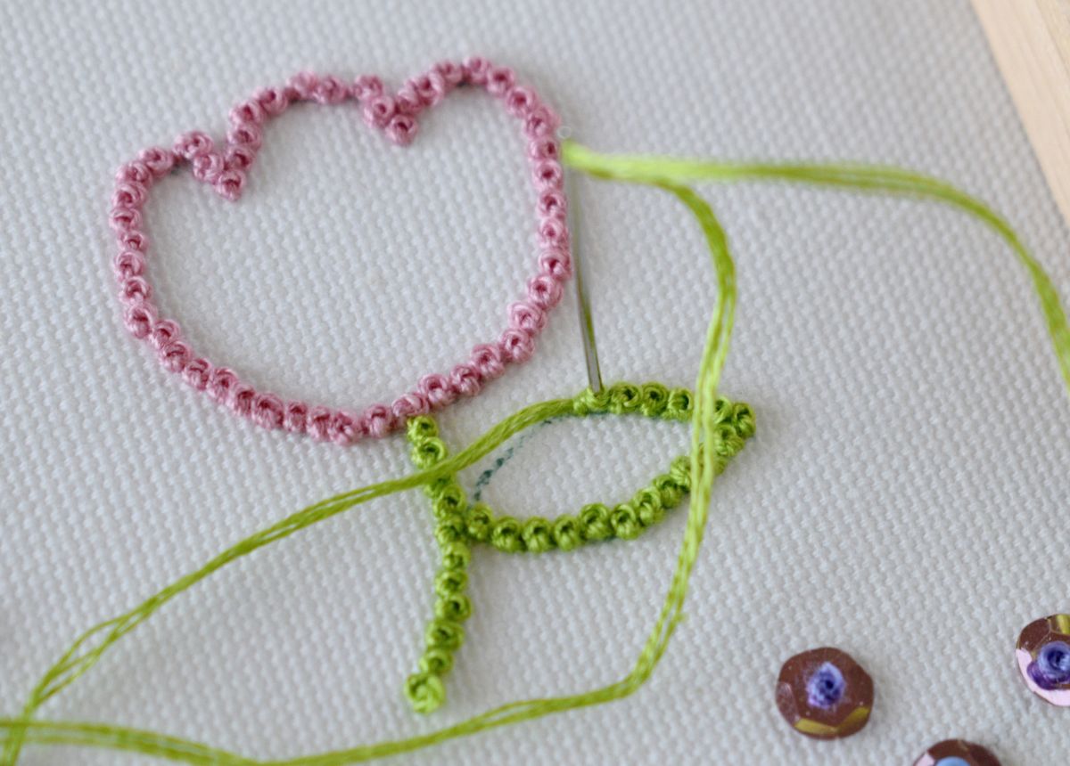green leaf embroidery outline with french knot stitch on white fabric