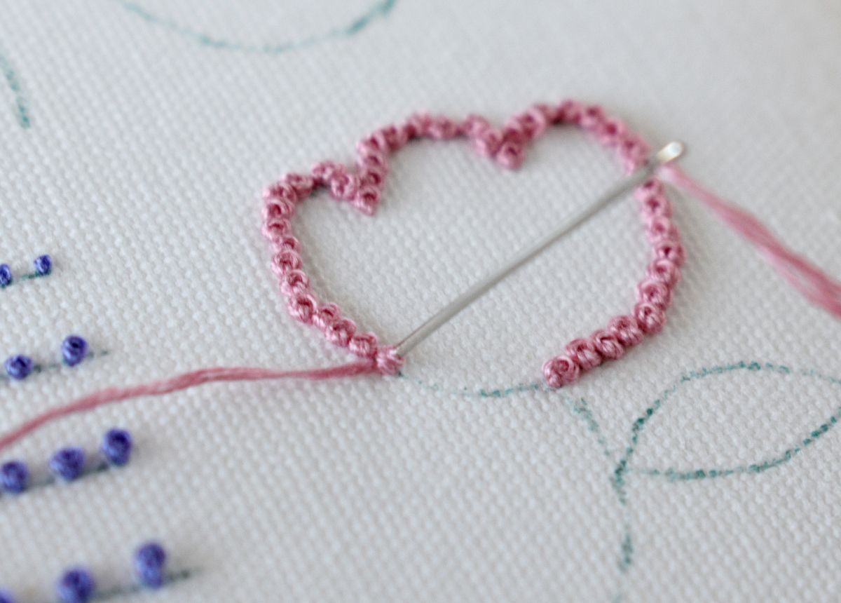 Pink flower embroidery made with French knot outline on white linen